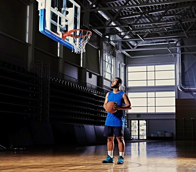Basketteur professionnel noir en action sur un terrain de basket.