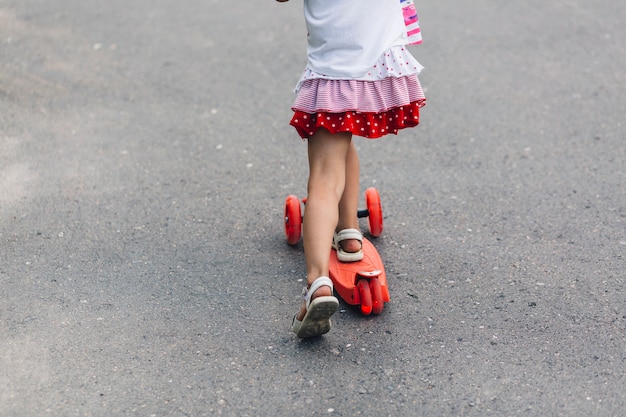 Basse section d'une fille trottinette sur la rue