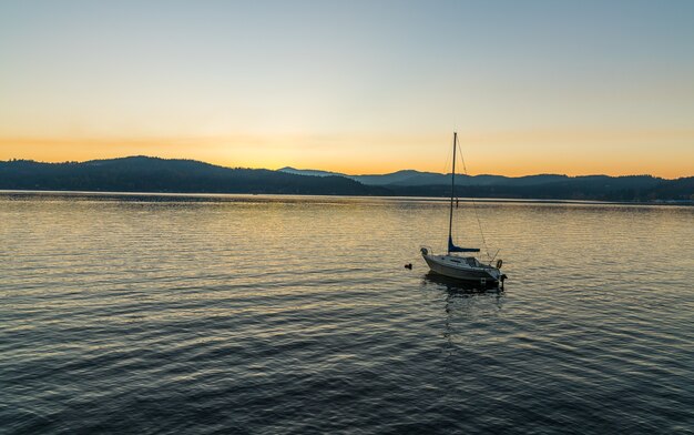 Bateau naviguant sur la mer avec des montagnes au loin pendant le coucher du soleil