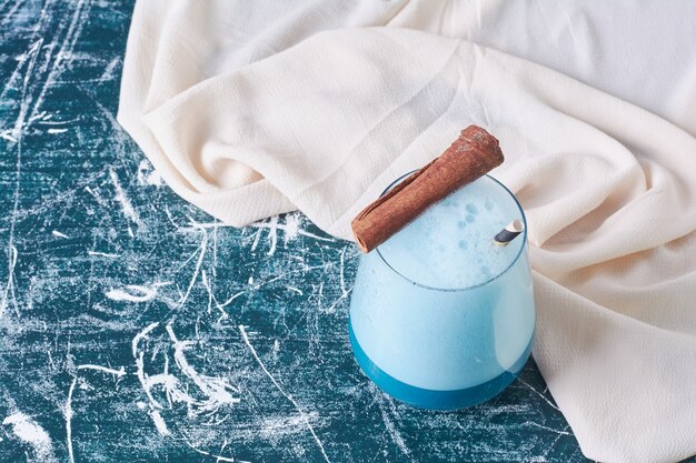 Bâton de cannelle avec une tasse de boisson sur bleu.