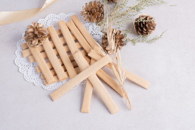 Bâtonnets de biscuits avec pomme de pin sur une surface blanche