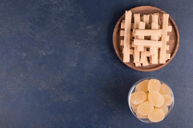 Bâtonnets de gaufres dans un tas de marmelades dans une tasse en verre