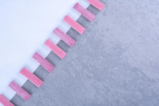 Photo gratuite bâtonnets de gomme violets alignés en diagonale le long de la bordure d'une feuille de papier sur une surface en marbre