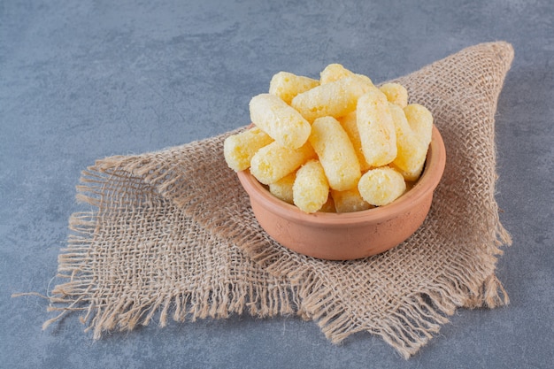 Bâtonnets de maïs sucré dans un bol, sur la texture, sur la surface en marbre