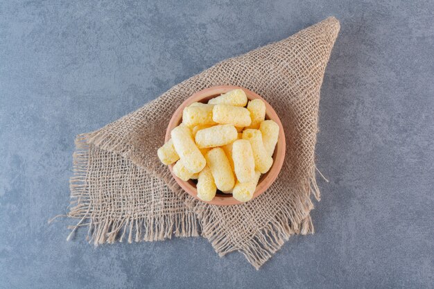 Bâtonnets de maïs sucré dans un bol, sur la texture, sur la surface en marbre