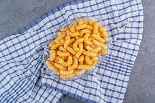 Bâtonnets de maïs sucré dans un bol sur un torchon, sur la surface en marbre