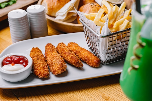 Bâtonnets de poulet avec frites mayonnaise ketchup sel poivre vue latérale