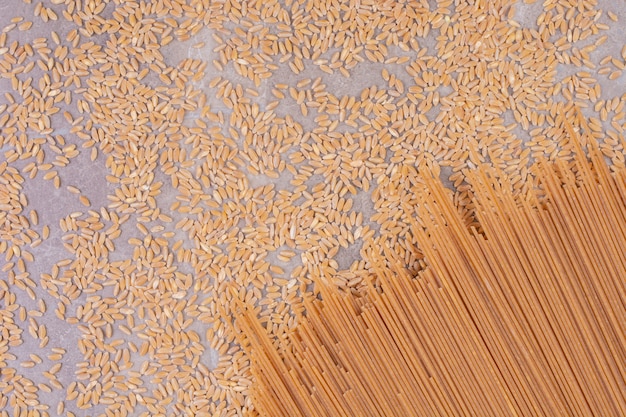 Bâtonnets de spaghetti crus et plants de blé sur le sol.