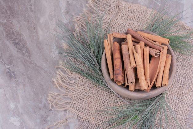 Bâtons de cannelle dans une tasse en bois avec une branche de chêne autour