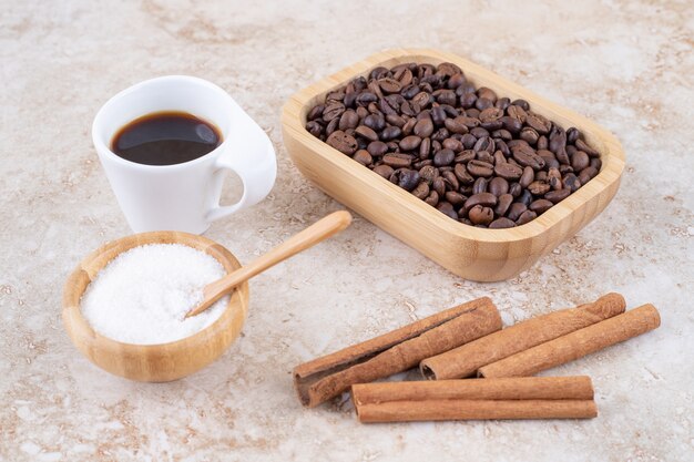Bâtons de cannelle, grains de café, sucre et une tasse de café