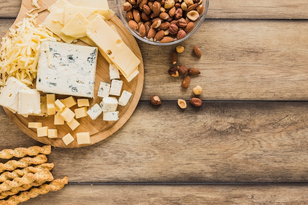 Bâtons de pain, bols de fromage râpé et d&#39;amandes sur un bureau en bois