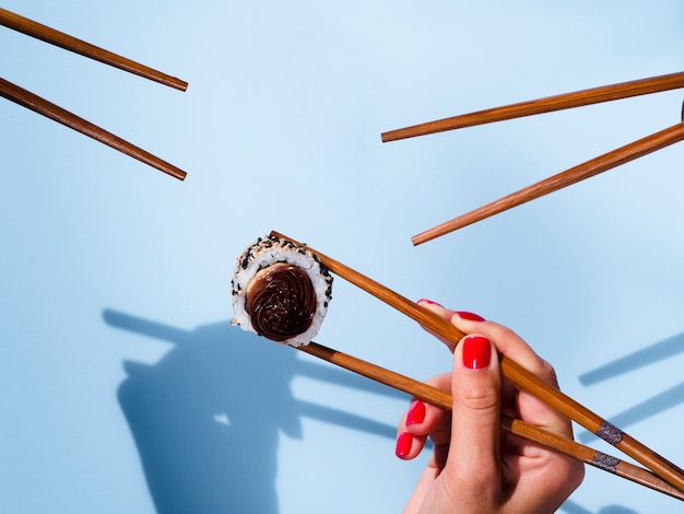 Des bâtons de sushi et un rouleau de sushi sur fond bleu