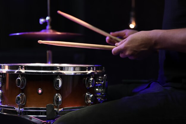 Batteur jouant des baguettes sur une caisse claire dans l'obscurité. Concept de concert et de performance en direct.