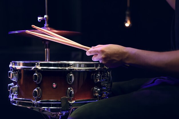 Batteur jouant des baguettes sur une caisse claire dans l'obscurité. Concept de concert et de performance en direct.