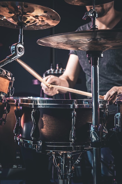 Un batteur masculin joue de la batterie dans une pièce sombre