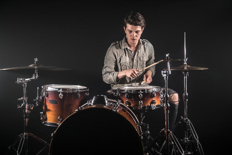 Photo gratuit batteur professionnel jouant sur batterie sur scène sur fond noir avec baguettes et look vintage. vue de dessus. effet de fumée