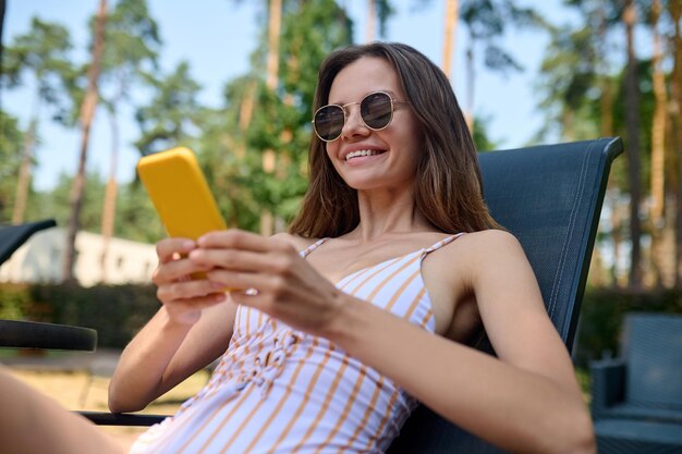 Bavardage. Jolie jeune femme lisant un message et souriant