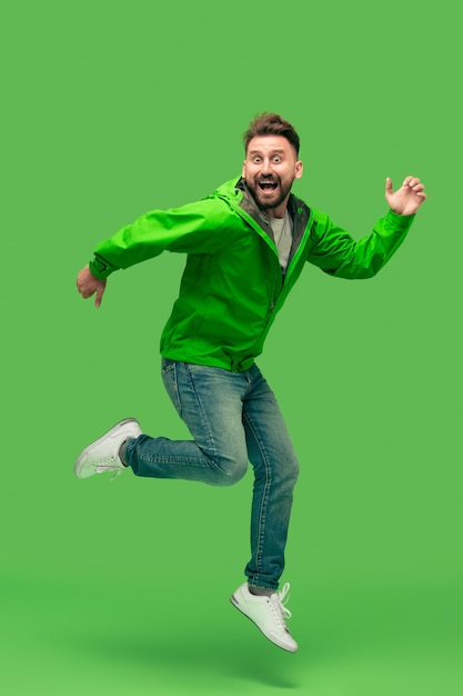 Photo gratuite beau barbu souriant heureux jeune homme en cours d'exécution isolé sur un studio vert branché vif