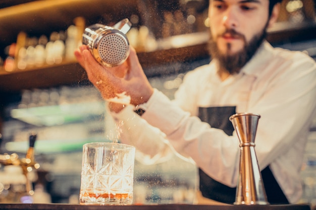 Beau barman faisant boire et cocktails au comptoir