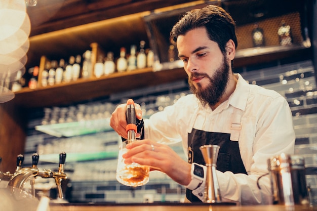 Beau barman faisant boire et cocktails au comptoir