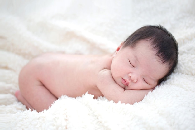 Beau bébé asiatique nouveau-né dormant sur une couverture à fourrure