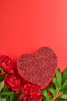 Beau bouquet de fleurs de pivoines rouges avec boîte cadeau rouge sur fond rouge, vue de dessus, espace de copie, mise à plat. saint valentin, fond de fête des mères.