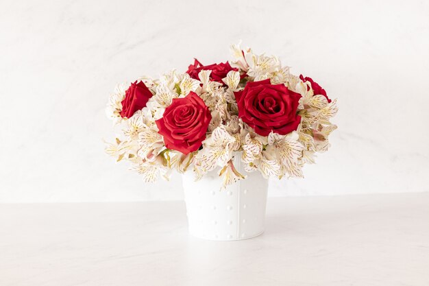 Beau bouquet de roses rouges et de fleurs de lys dans une boîte