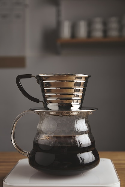 Photo gratuite beau côté de la cafetière goutte à goutte chrome transparent avec café filtré torréfié, isolé sur une table en bois épaisse dans un café. poids blancs. vapeur. brutal.