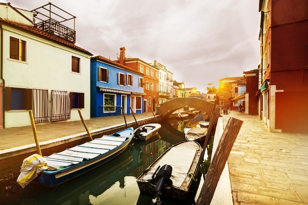 Beau coucher de soleil avec bateaux, bâtiments et eau. Lumière du soleil. Toning. Burano, Italie.