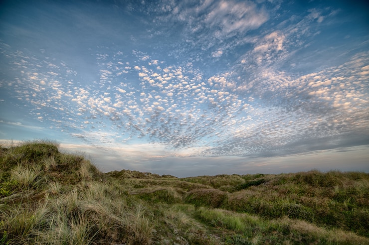 Photo gratuit beau coup un champ sur une colline sous le ciel nuageux