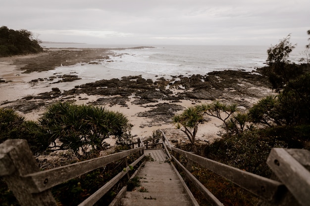 Photo gratuite beau coup d'escalier en bois vers le rivage près de la mer avec un ciel nuageux en arrière-plan