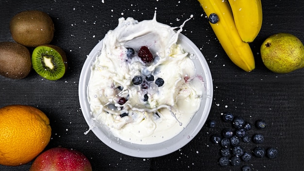 Photo gratuite beau coup de fruits exotiques et un bol de lait avec quelques myrtilles tombant dedans