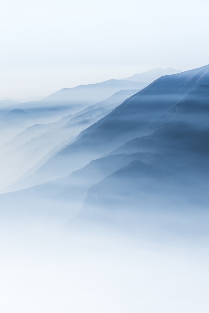 Photo gratuite beau coup de hautes collines blanches et de montagnes couvertes de brouillard