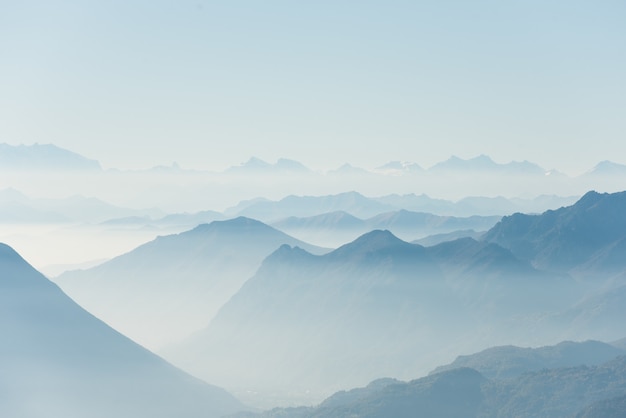 Beau coup de hautes collines blanches et de montagnes couvertes de brouillard