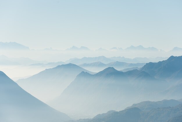 Beau coup de hautes collines blanches et de montagnes couvertes de brouillard