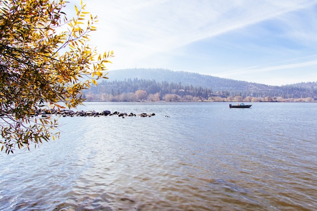 Photo gratuite beau coup d'un lac avec un bateau naviguant dessus avec un ciel ensoleillé