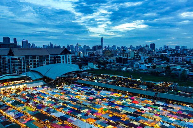 Beau coup de tentes de marché près des bâtiments sous un ciel bleu nuageux