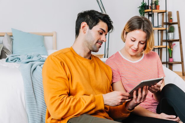 Beau couple à l&#39;aide de tablette près du lit