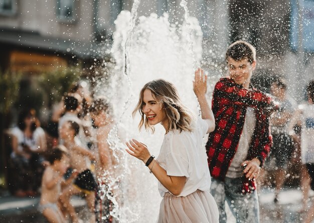 Le beau couple amoureux jouant avec la fontaine