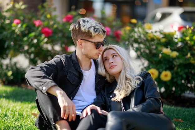 Un beau couple assis sur l'herbe et la fille regardant son petit ami Photo de haute qualité