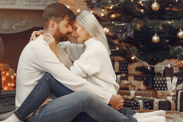 Beau couple assis à la maison près de l'arbre de Noël
