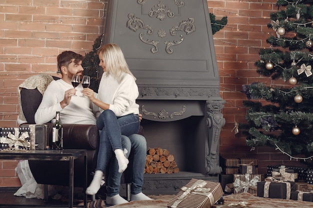 Beau couple assis à la maison près de l'arbre de Noël