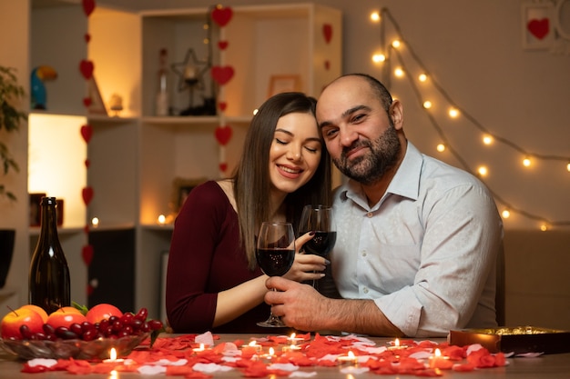 Beau couple assis à la table décorée de bougies et de pétales de rose, passer la soirée ensemble