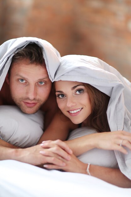 Beau couple au lit sous les couvertures.