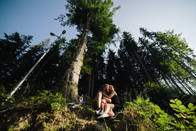 Un beau couple et un chien se reposent dans la forêt