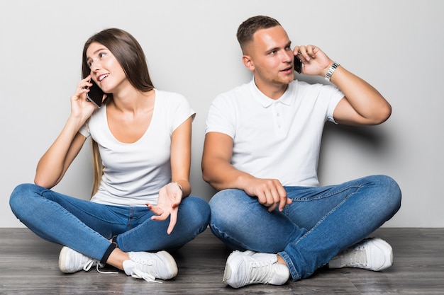 Beau couple élégant parlant au téléphone ensemble isolé sur fond blanc