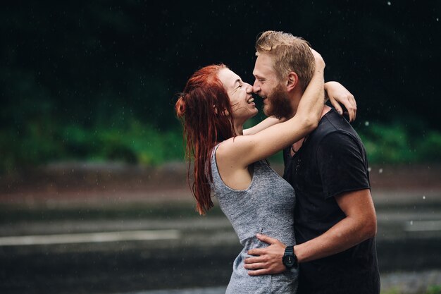 Beau couple étreignant dehors sous la pluie
