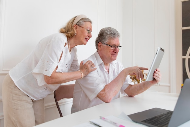 Beau couple de grands-parents apprenant à utiliser un appareil numérique