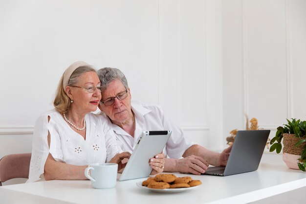 Beau couple de grands-parents apprenant à utiliser un appareil numérique