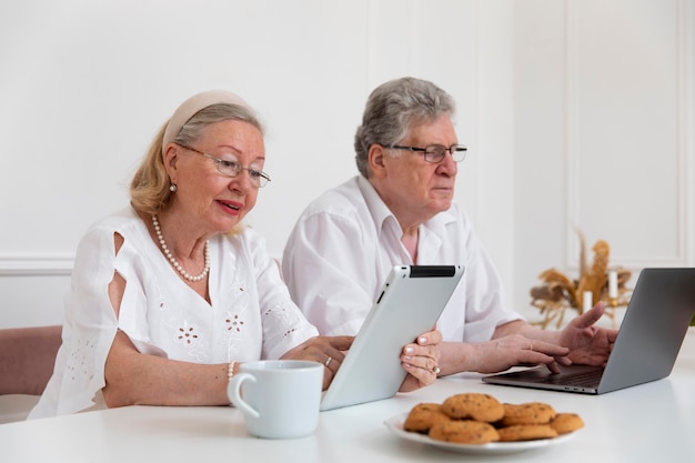 Beau couple de grands-parents apprenant à utiliser un appareil numérique